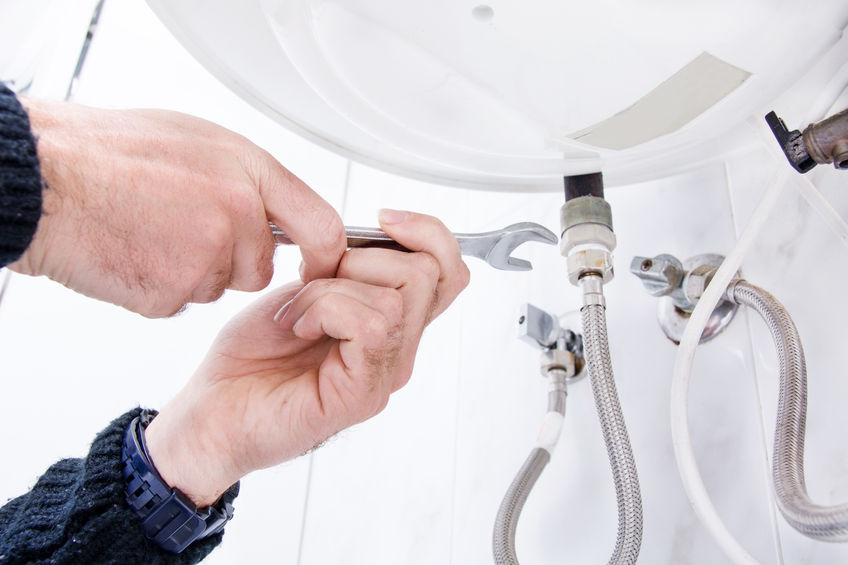 A technician repairing a sink pipe